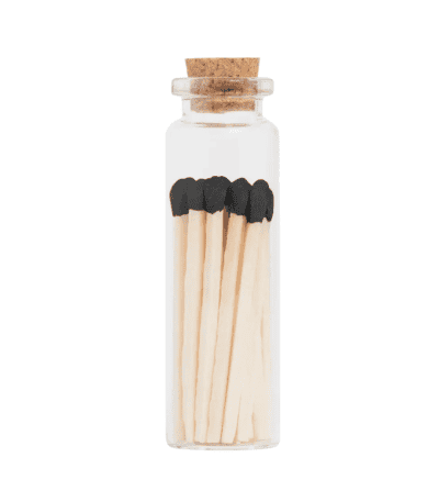 Petite glass jar with black-tipped wooden matches and cork lid for safe storage.