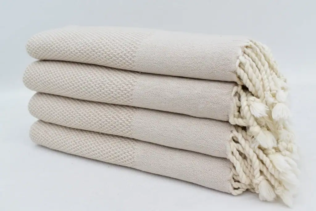 Soft, cream-colored woven towels stacked neatly, showcasing quality and comfort for home or spa use.