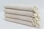 Soft, cream-colored woven towels stacked neatly, showcasing quality and comfort for home or spa use.