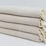 Soft, cream-colored woven towels stacked neatly, showcasing quality and comfort for home or spa use.
