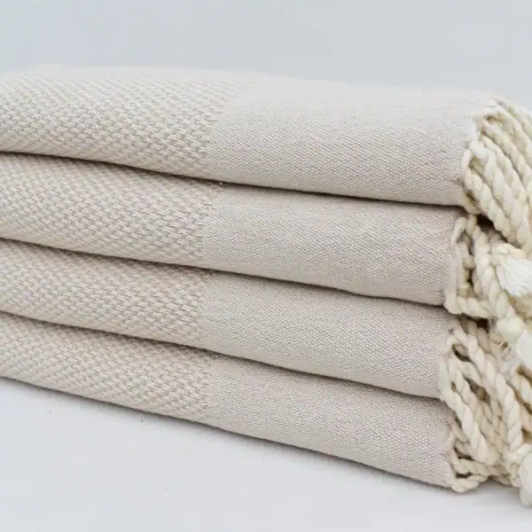 Soft, cream-colored woven towels stacked neatly, showcasing quality and comfort for home or spa use.