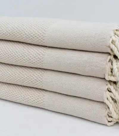 Soft, cream-colored woven towels stacked neatly, showcasing quality and comfort for home or spa use.