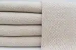 Soft beige textured fabric upholstery with a subtle houndstooth pattern.