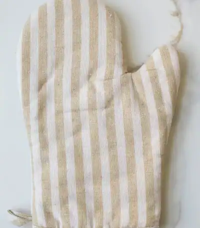 Linen oven mitt with beige and white vertical stripes for kitchen use.