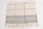 Soft beige and gray striped woven textile with fringed edges, ideal for home decor or as a decorativ.