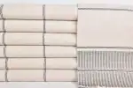 Soft beige and gray woven textiles stacked and draped, showcasing natural fabric textures and subtle.