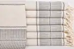 Soft, neutral-colored woven textiles with striped patterns, neatly folded and stacked.