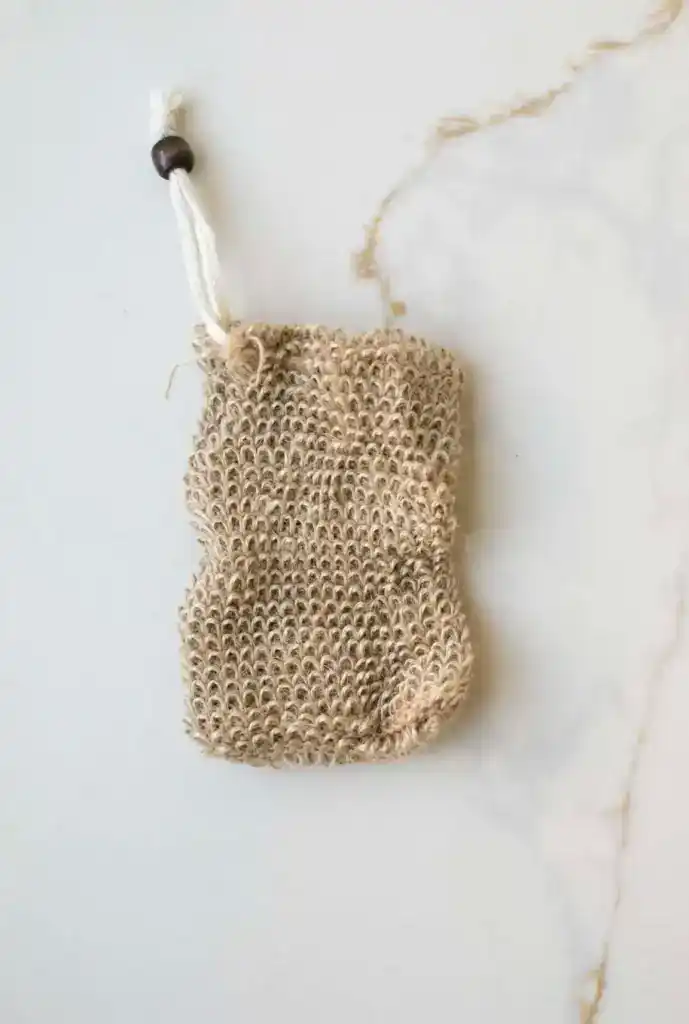 Natural jute soap saver pouch with drawstring closure designed to create rich lather, gently exfoliate skin, and extend the life of soap bars in an eco-friendly bath routine.