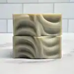 Gentle soap bars with marbled black, white, and gray swirls on a white tiled background.