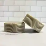 Gentle soap bars with marbled design on a white tiled background.