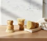 Soft-bristled bamboo cleaning brushes on wooden surface with marble background.