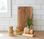 Soft-bristle wooden cleaning brushes with a plant on a kitchen countertop, minimalistic decor.