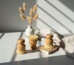 Soft-bristle wooden body brushes with natural fibers on a white speckled surface.