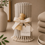 Luxury kitchen cleaning gift set featuring a rolled organic Turkish towel, natural wooden sisal scrub brush, cream ribbon bow, and Nurtured branded gift tag styled in a warm neutral kitchen setting.