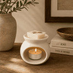 White ceramic wax melter with glowing tealight candle and floral wax melt cube, styled on a rustic wooden surface with warm neutral décor and soft ambient lighting.