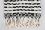 Black and white striped woven textile with fringe detail, ideal for home decor or accessories.
