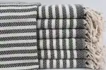 Black and white striped woven blankets stacked neatly with fringed edges.