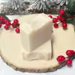 Gentle soap bars on a wooden slice with red berries and greenery, perfect for natural skincare.