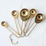 Stainless steel (gold finished) measuring spoons set on white marble background, kitchen utensils, cooking tools, culinary acce.