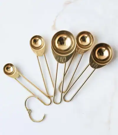 Stainless steel (gold finished) measuring spoons set on white marble background, kitchen utensils, cooking tools, culinary acce.