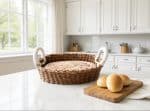 Wicker basket with a lid on a white kitchen countertop, fresh bread nearby.