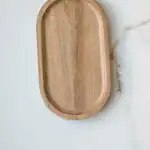 Wooden serving tray on white marble surface, minimalist kitchen accessory.