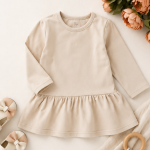 Organic cotton long sleeve baby dress with gathered skirt in a soft neutral cream color.